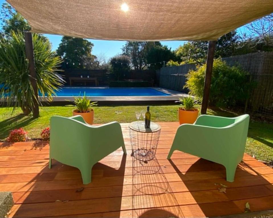 a patio with two green chairs and a bottle of wine at Woodstock Suite in Nelson