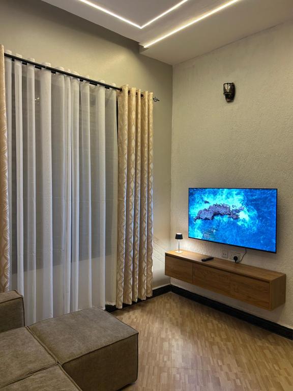 a living room with a flat screen tv on a wall at Vn mbeya apartment in Mbeya