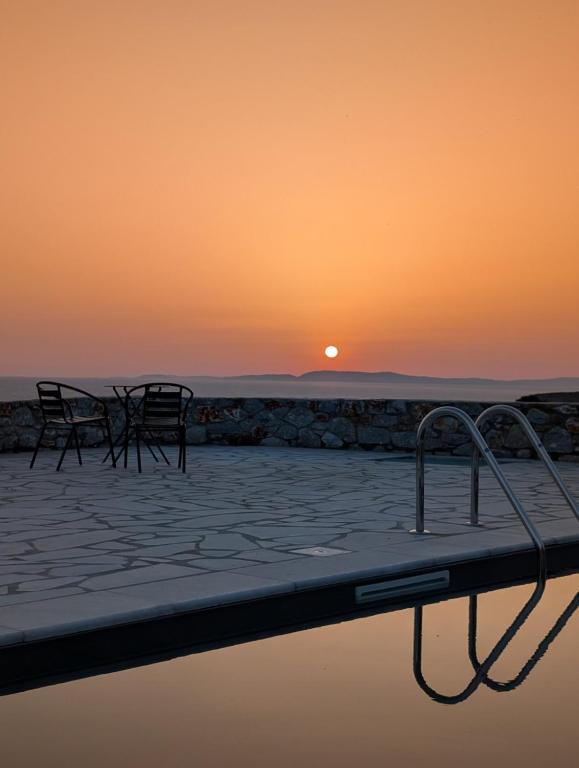 a pool with chairs and the sunset in the background at Thelea Mani in Kafióna