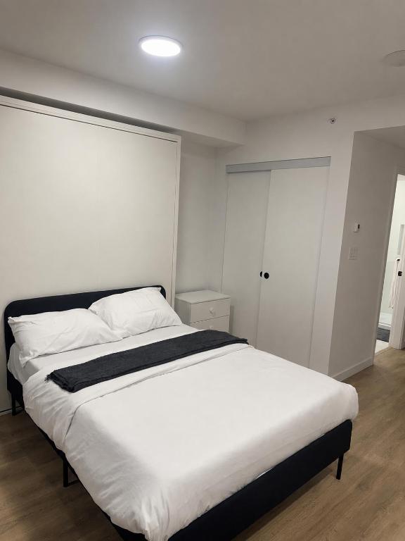 a bedroom with a large bed with white sheets at Executive suite in Surrey