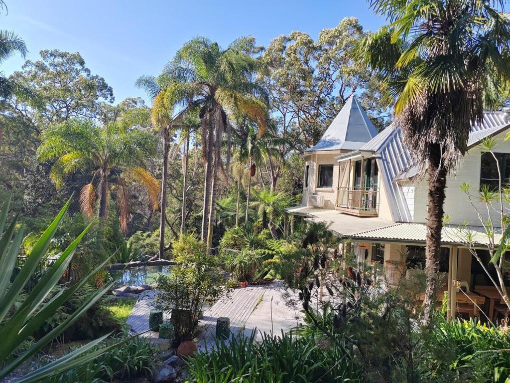 a house with a swimming pool and palm trees at Gorge Castle in forest landscape in Galston