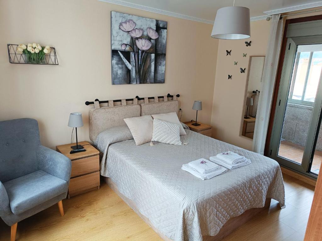 a bedroom with a bed and a chair and a window at Piso PLAYA CANGAS CENTRO in Cangas de Morrazo
