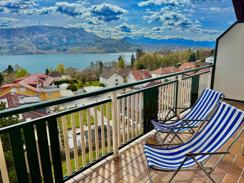 two chairs on a balcony with a view of the water at Apartment Karawankenblick with Lake View - Free Parking in Pörtschach am Wörthersee