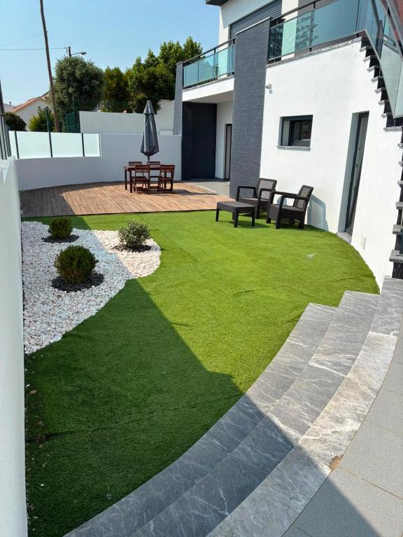 a small yard with grass and benches on a house at Villa Pérola Pestana in Lourinhã