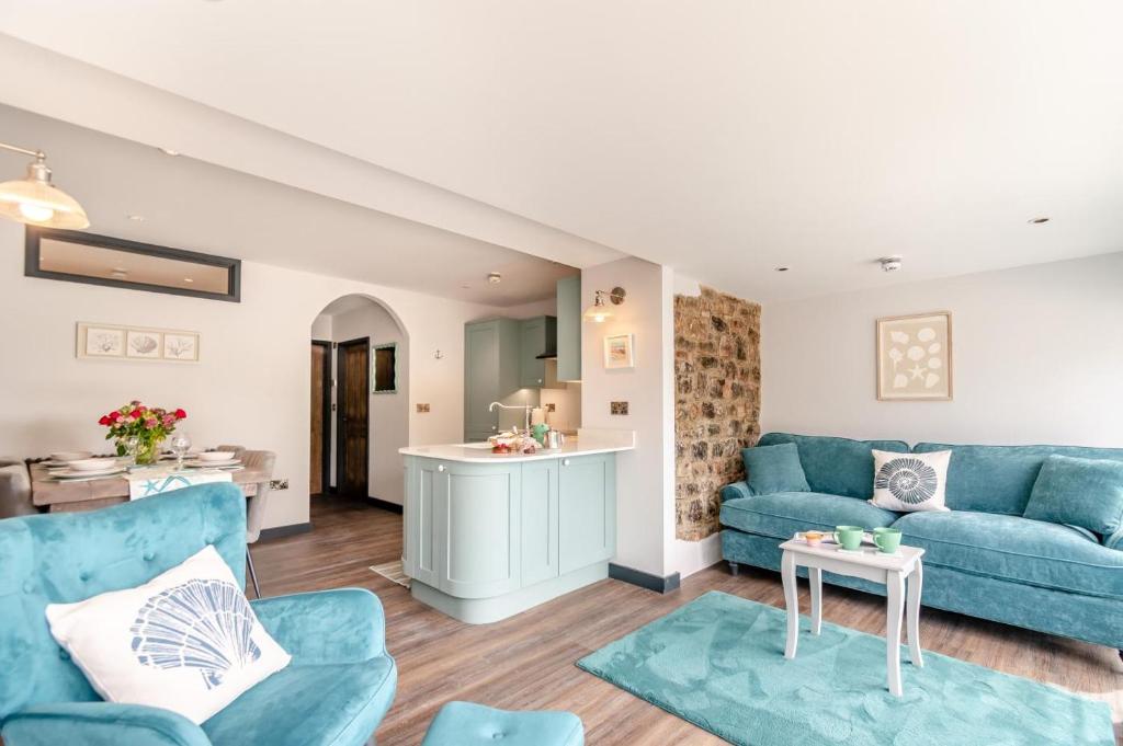 a living room with blue couches and a kitchen at 2 Bed in Tenby oc-b41400 in Tenby