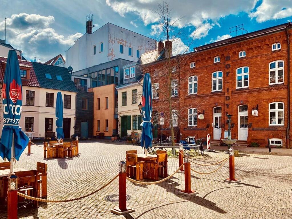 a courtyard with tables and blue umbrellas and buildings at Courtyard Idyll Apartment in Rostock