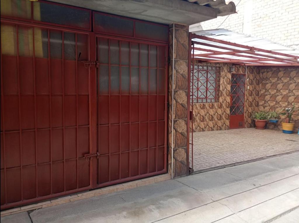 a red garage door on a building with a patio at VillaHouse - Huaraz in Huaraz
