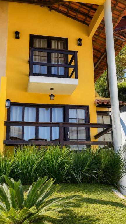 a yellow house with black windows and a balcony at Refúgio das Rosas in Pedro do Rio