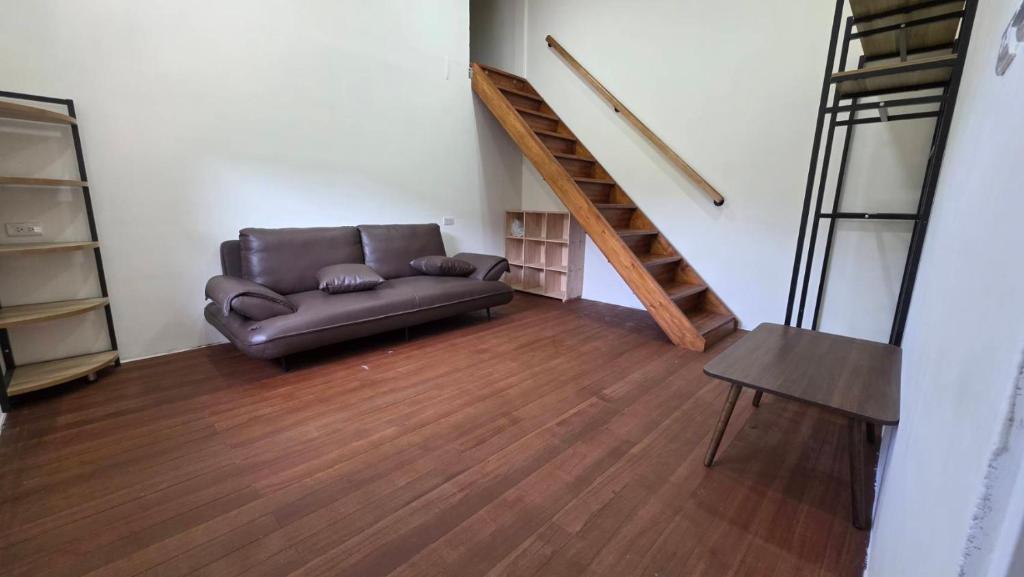 a living room with a leather couch and a staircase at 如家小憩 in Shui-t'ien