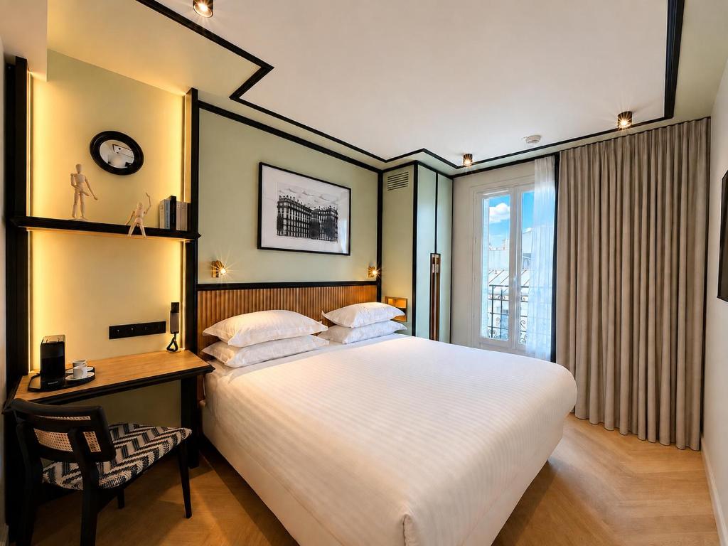 a bedroom with a bed and a desk and a clock at Hotel Maison Lenoir in Paris