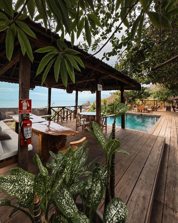 a wooden deck with a table and a swimming pool at El Xalli Hotel in El Zonte