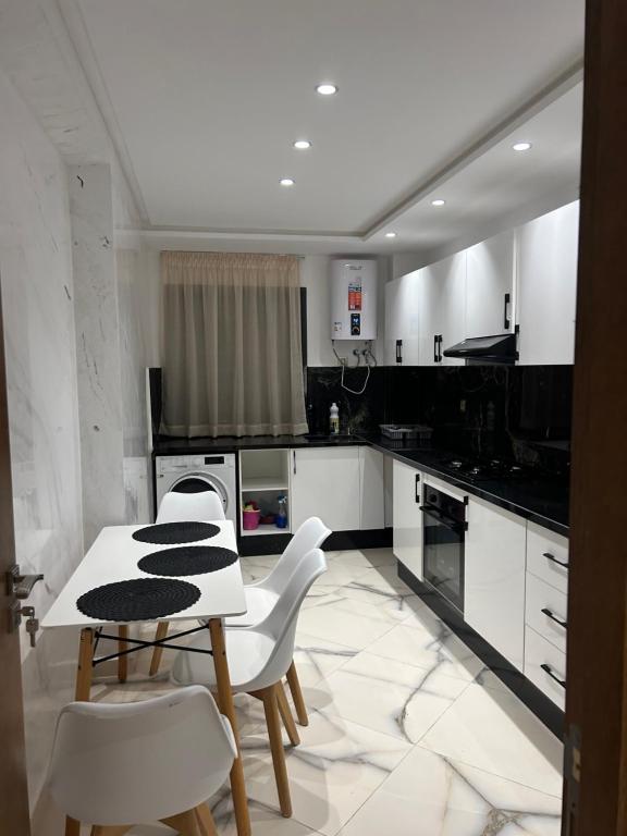 a kitchen with white cabinets and a table and chairs at belle appartement à centre Kénitra in Kenitra