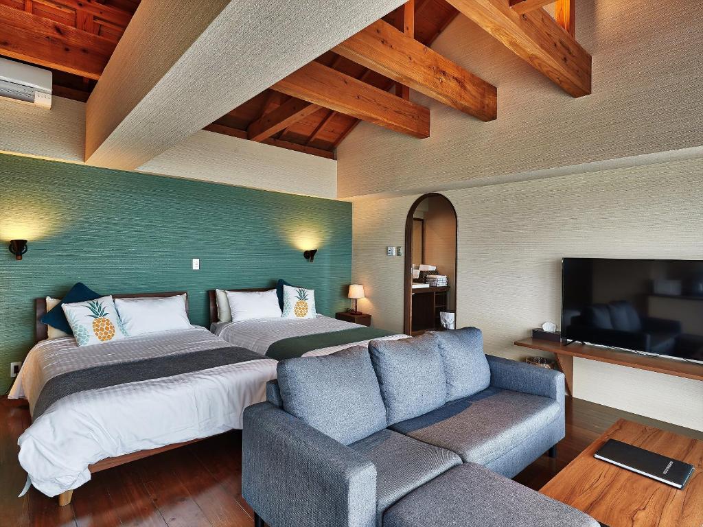 a hotel room with two beds and a couch at Nagahama Beach Resort Kanon in Nakijin