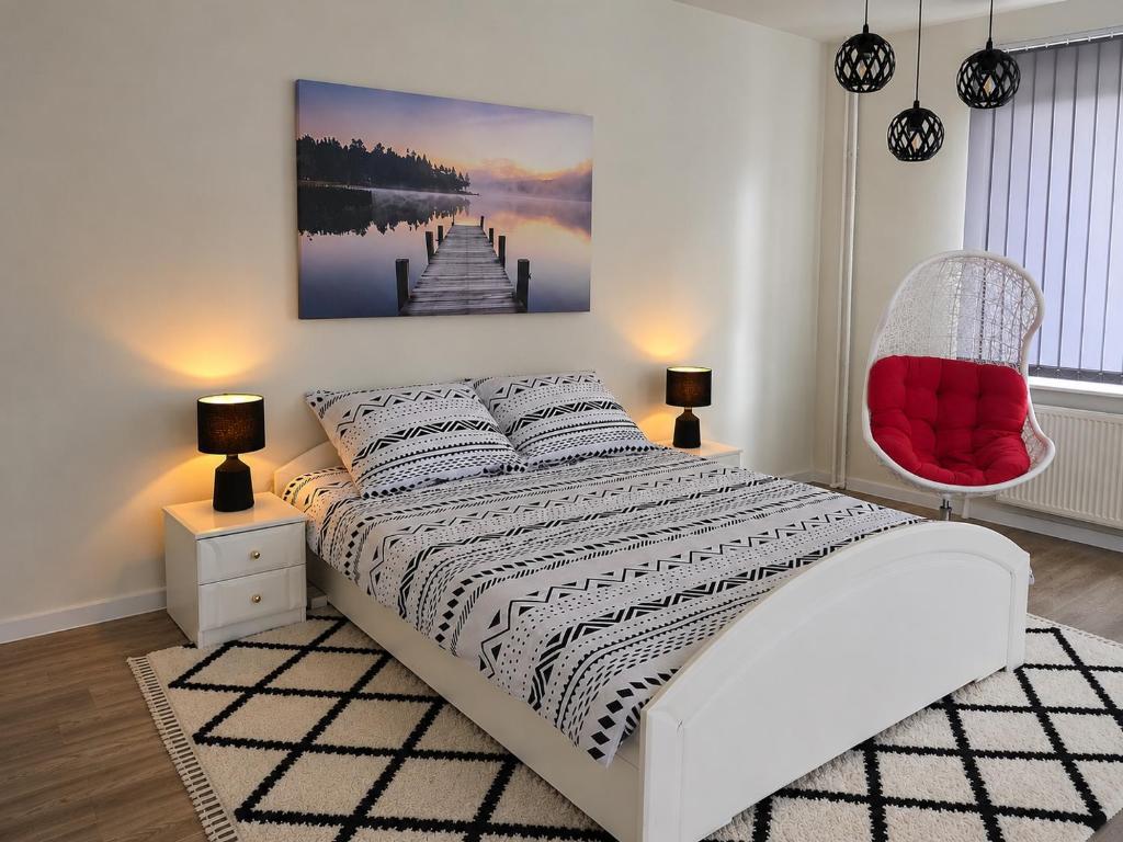 a bedroom with a white bed and a red chair at WlodawaSpot in Włodawa