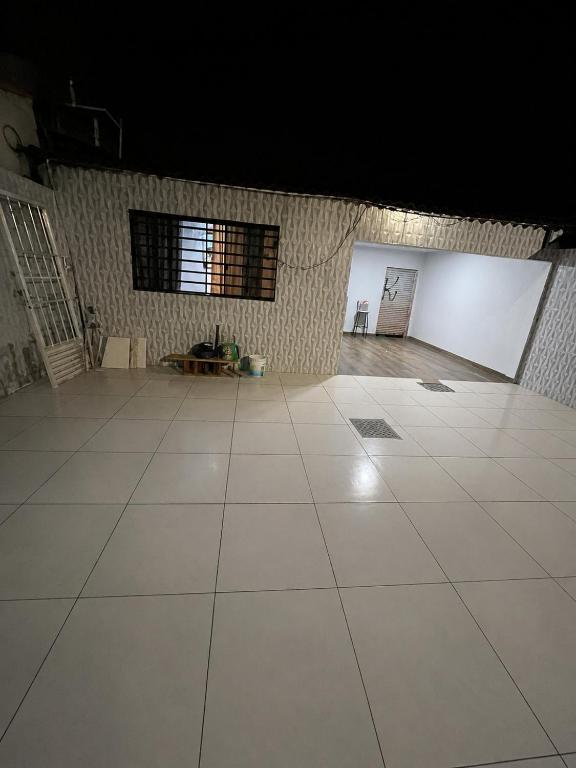 a large room with a white tile floor and two windows at Vieira House in Brasília