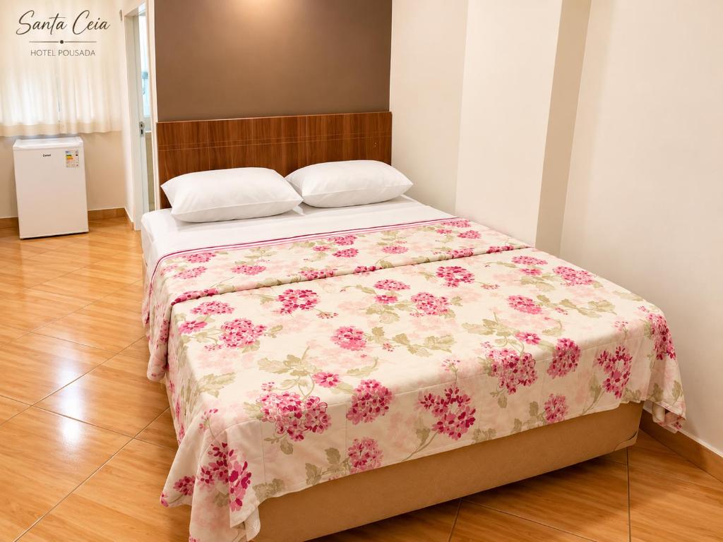 a bedroom with a bed with a floral bedspread at Hotel Pousada Santa Ceia in Aparecida