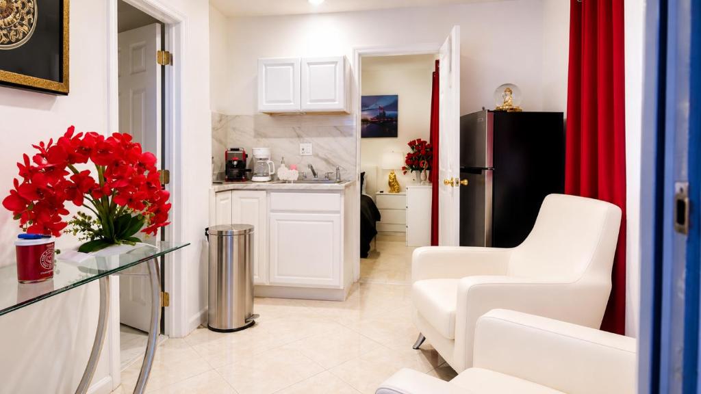 a kitchen with white cabinets and red flowers on a table at Private Miami Suite in Tamiami Airport