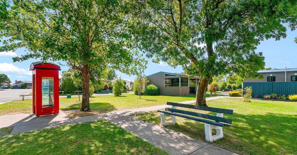 a red phone booth and a bench in a park at Traralgon Holiday Village in Traralgon