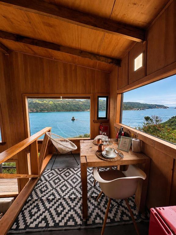 a cabin with a table and a view of the water at Pumillahue Lodge cabaña matrimonial in Ancud