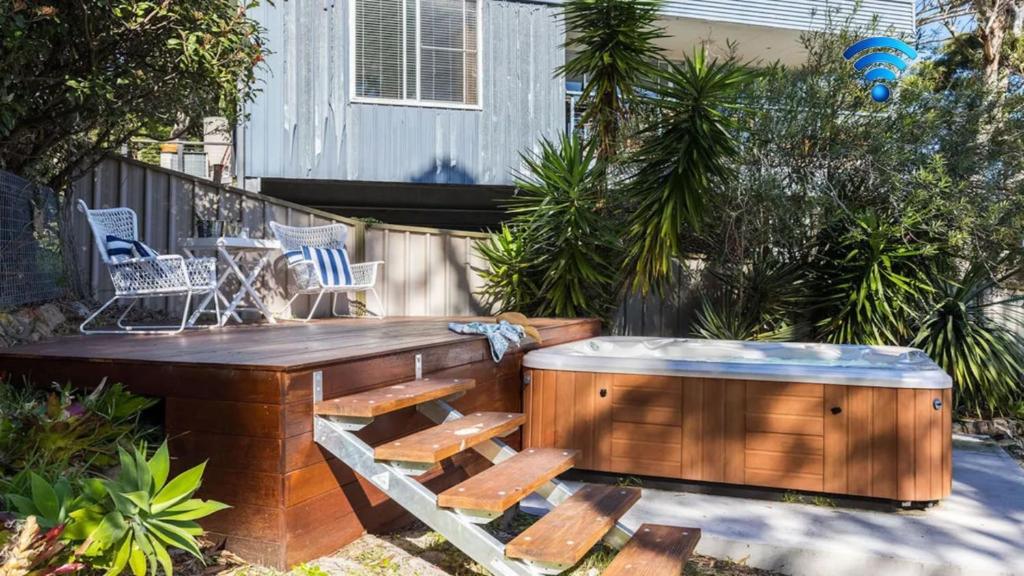 a patio with a wooden bench and a hot tub at Shoal Bay Oasis in Shoal Bay