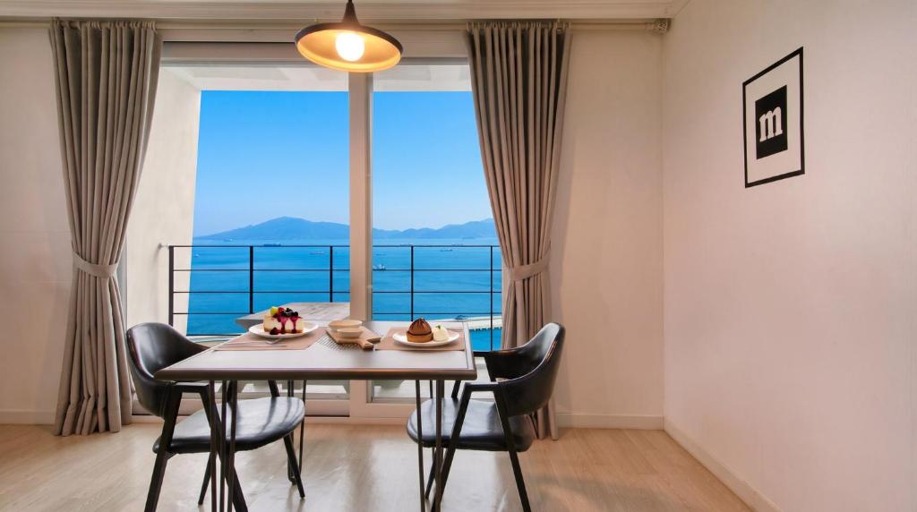 a dining room with a table and chairs and a large window at Yeosu Harushimpyo Pension in Yeosu
