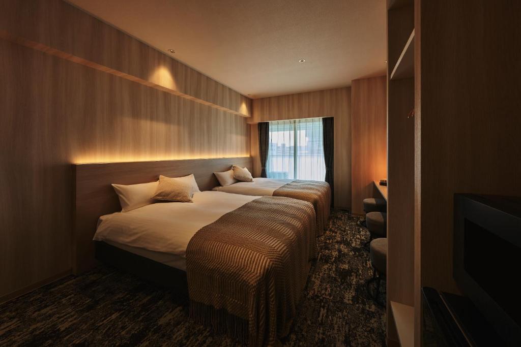 a hotel room with two beds and a television at Moat Inside Hakata in Fukuoka