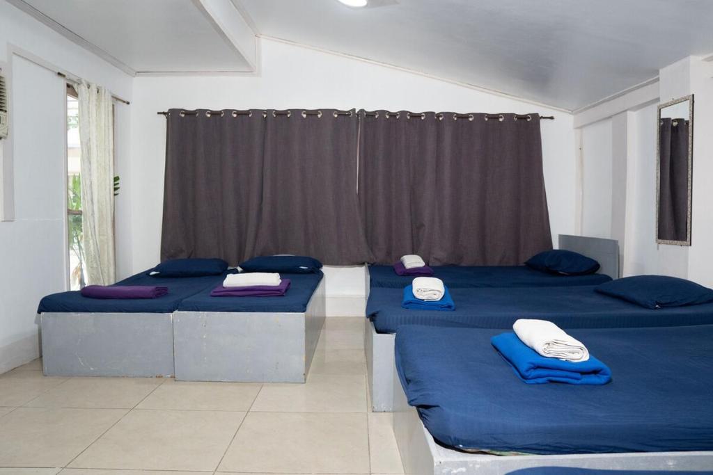 a room with two beds with blue sheets and a window at En Pensionne Comfort in Iloilo City