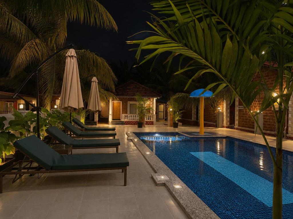 a swimming pool with lounge chairs and an umbrella at Baga beach heritage resort in Calangute