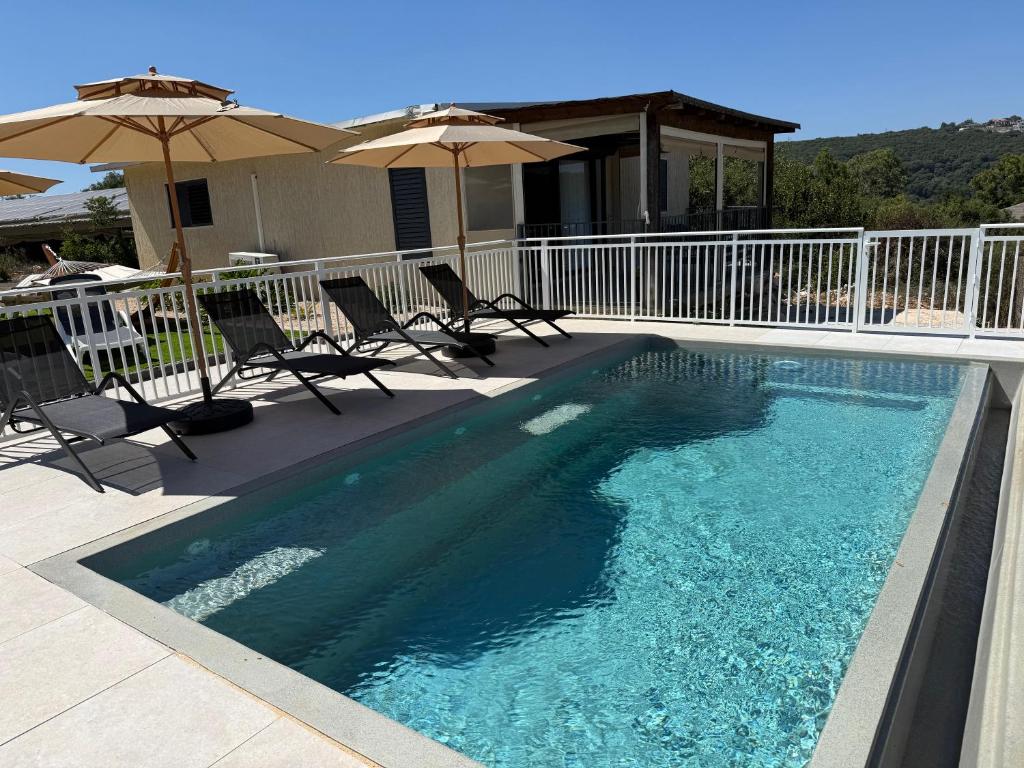 a swimming pool with chairs and umbrellas on a house at סוויטות שריתא in Shomera