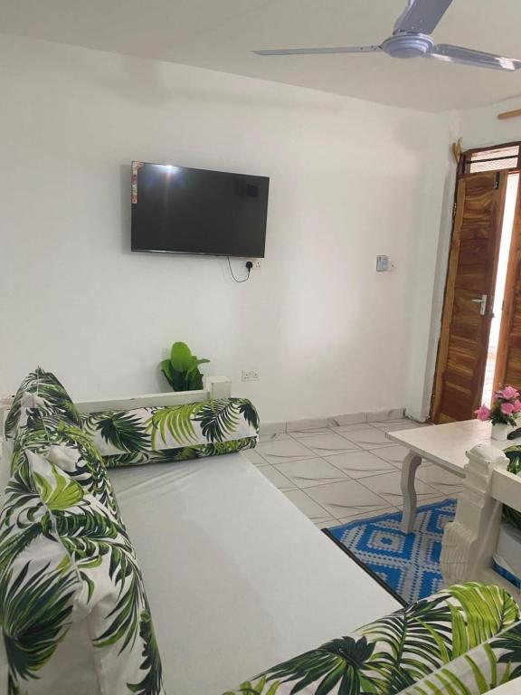 a living room with a couch and a flat screen tv at Havilla Cecilia in Watamu