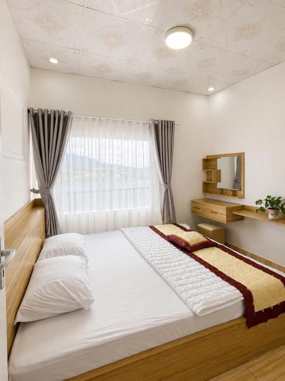 a large white bed in a room with a window at Lakshmi 2BR House Da Lat in Ấp Phước Thánh