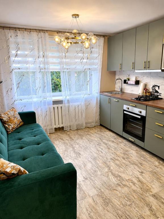 a living room with a green couch and a kitchen at SMART flat - Ranna 49 in Sillamäe
