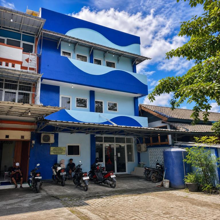 a blue building with motorcycles parked in front of it at Ava Guesthouse Lampung in Tanjungkarang