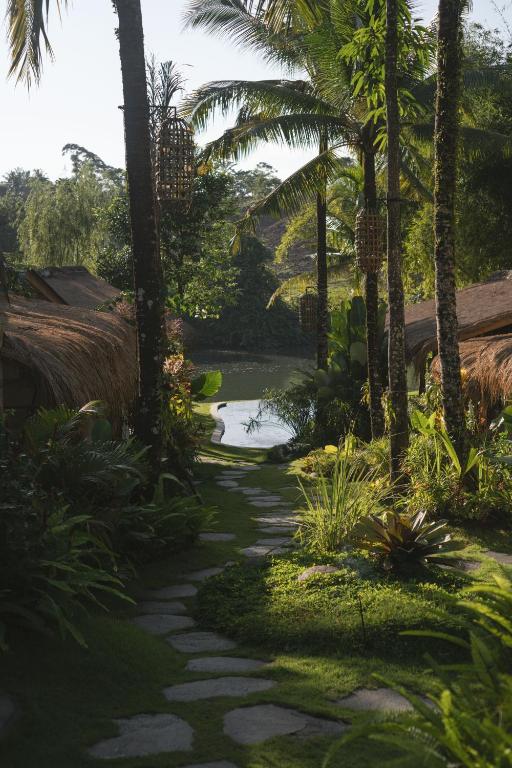 a garden with palm trees and a walkway at Yama Balian in Tabanan