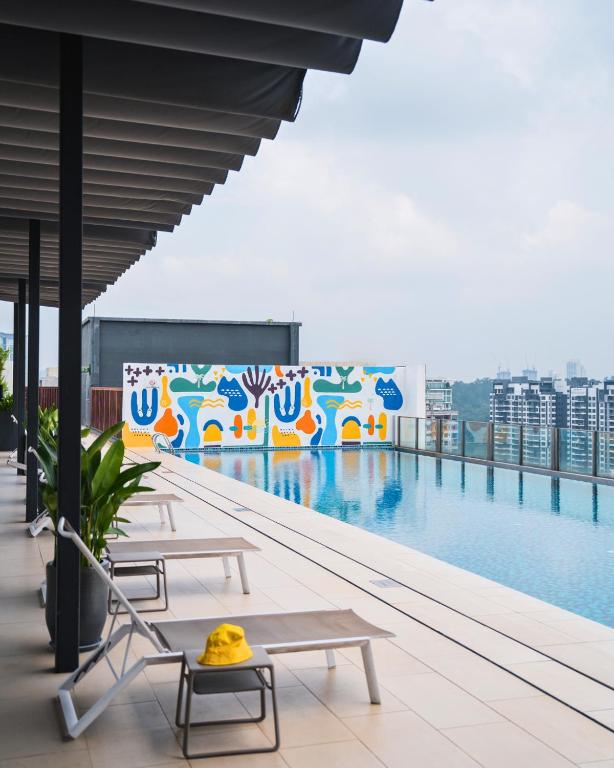 A rooftop pool deck lined with loungers and overlooking the city.