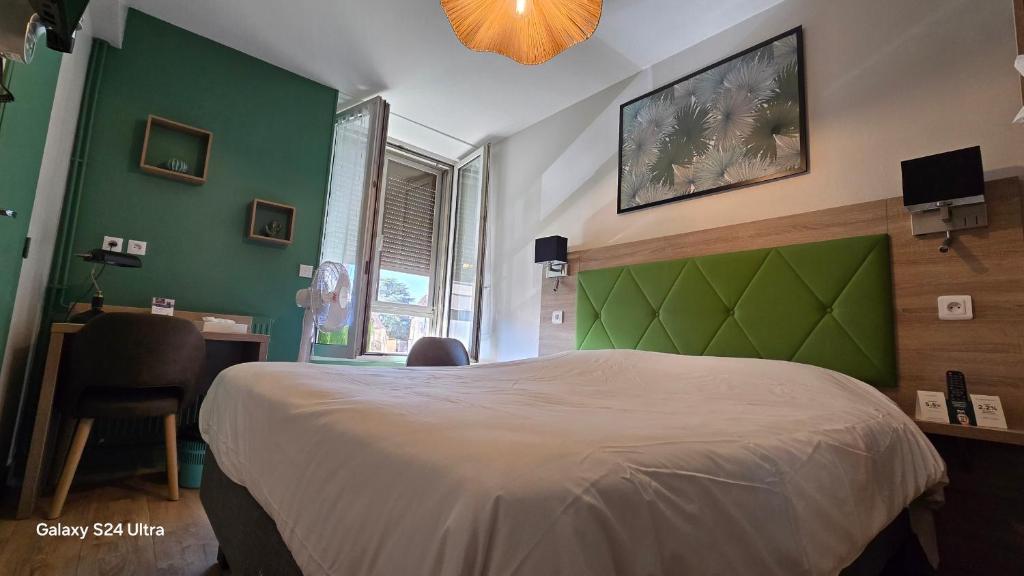 a bedroom with a large bed with a green headboard at Logis Hôtel Au Croissant in Buzançais