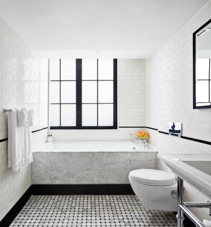 a white bathroom with a tub and a toilet at Walker Hotel Greenwich Village in New York
