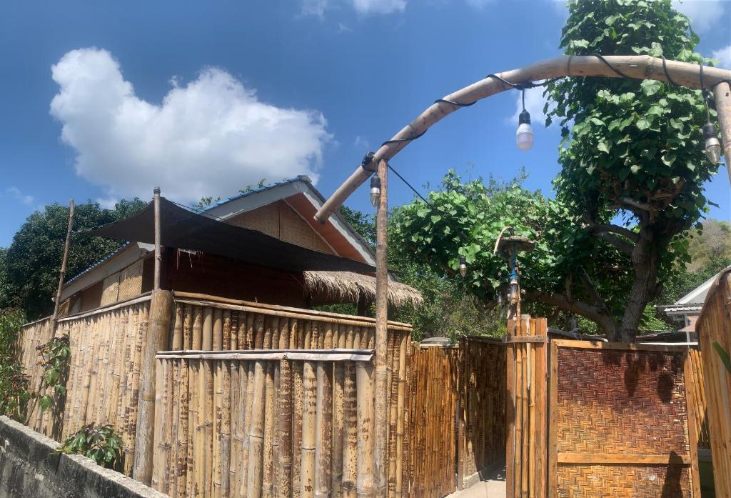 a wooden fence with a house behind it at Balee kayuu in Gili Gede
