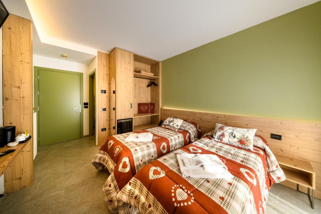 two beds in a room with green walls at Hotel Club Funivia in Aprica
