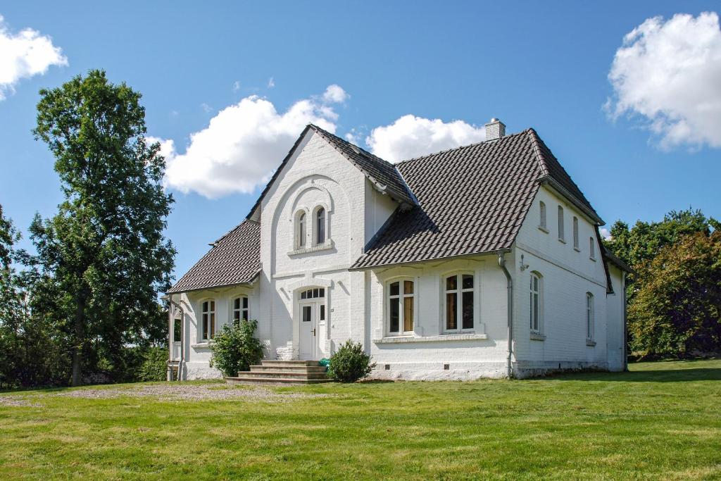 a white house with a black roof on a field at Gutshaus Glowitz in Glowitz