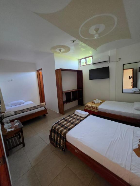 a hotel room with two beds and a flat screen tv at Hostal El Pinzón in Puerto Ayora