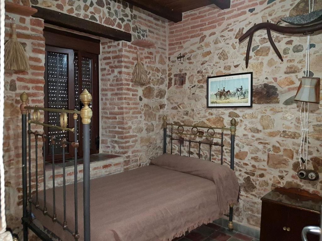 エル・ペドロソにあるEl Prado 11 Casa Ruralのレンガの壁にベッド1台が備わるベッドルーム1室