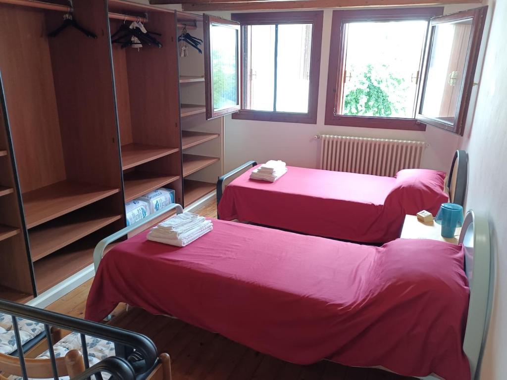 two beds in a room with pink sheets at Corte Maria in Vicenza
