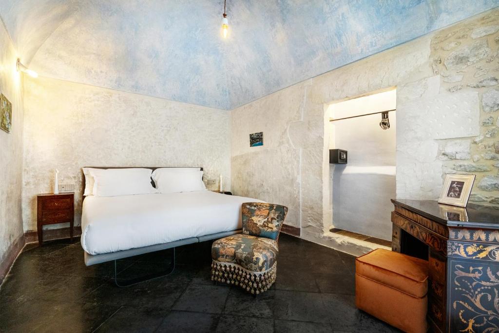 a bedroom with a bed and a chair in a room at P43 Sicilian Suites in Ragusa