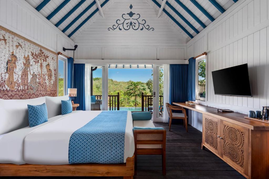 a bedroom with a bed and a desk with a television at Emana Aruna in Toyapakeh