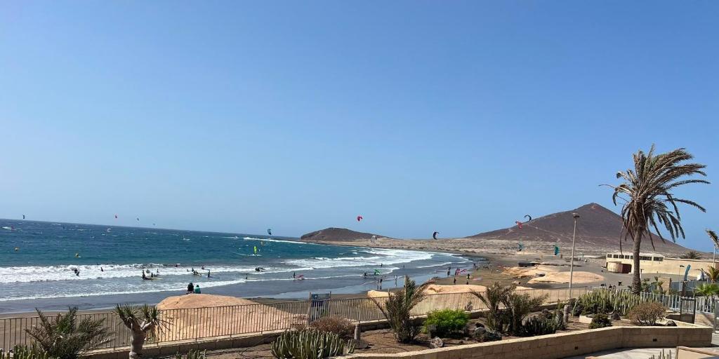 a beach with palm trees and people in the water at Casa Médano 12 in El Médano