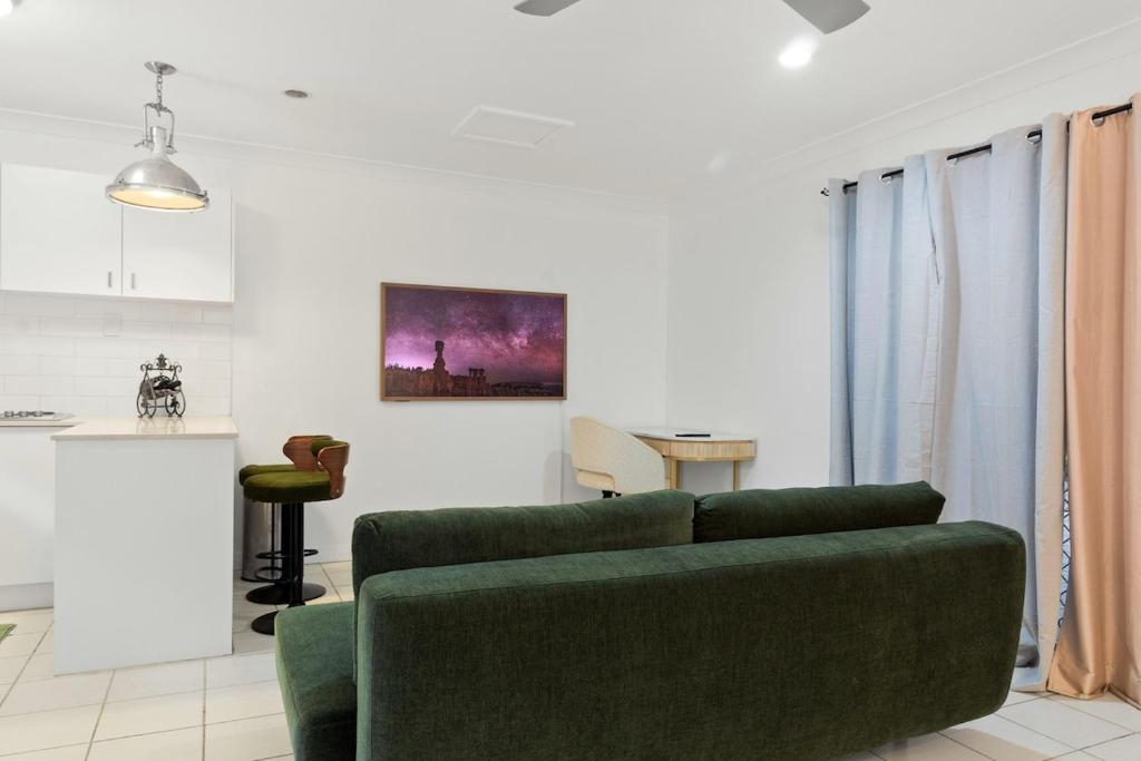 a living room with a green couch and a kitchen at Elegant & Cozy Private Studio in Wellington Point