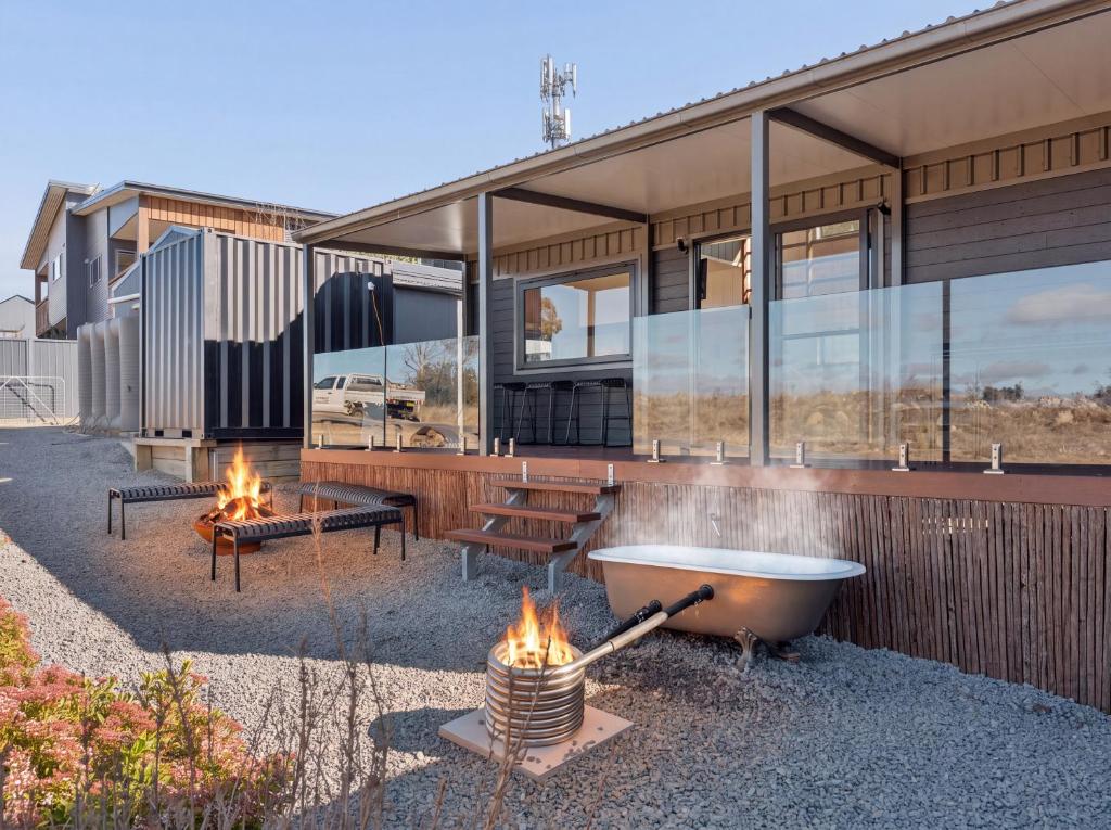a house with a bath tub and fires in front of it at Ginger GOAT - Luxury New Tiny Home in Jindabyne