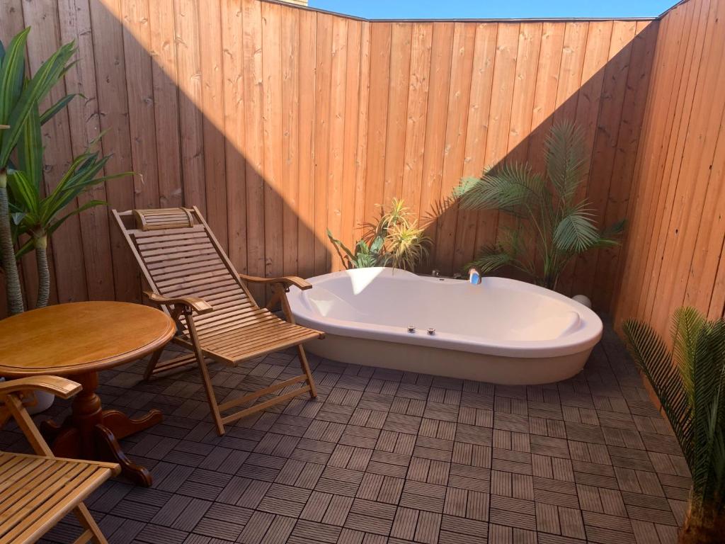 a bath tub on a patio with a table and a chair at Rplus八千代 in Chiba