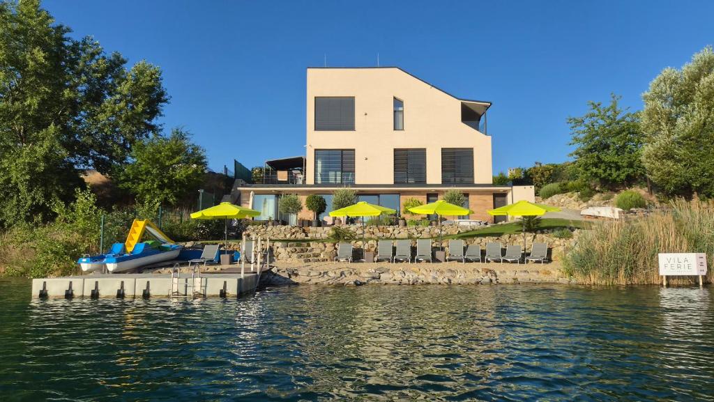 a house with yellow umbrellas in front of the water at Vila FERIE in Nová Lipnica